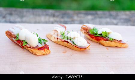 Fingerfood, Bruschettas mit Salat, Käse, Speck, Mozzarella auf Holztisch. Stockfoto