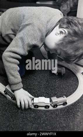 1970er Jahre, historisch, ein junger Schuljunge zu Hause, der mit seinem hölzernen Zug spielt, England, Großbritannien. Stockfoto