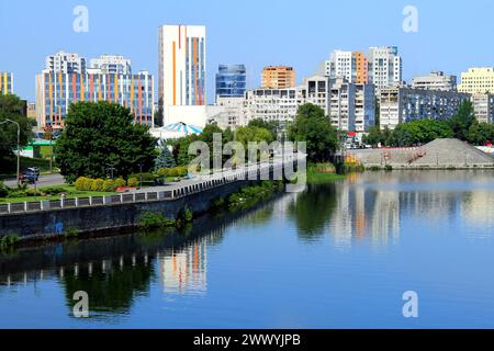 Eine große Stadt am Ufer des breiten Flusses. Wunderschöne moderne Türme, Gebäude, Wolkenkratzer spiegeln sich am Sommermorgen im Wasser. Ukrainische Stadt Dnipro, U Stockfoto