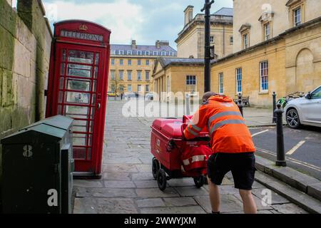 2024. März: Der Postbote der Royal Mail schiebt seinen Wagen in Bath, England, einen Hügel hinauf. Stockfoto