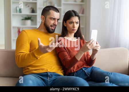 Ein Paar, das auf das Telefon mit Ausdrücken schaut Stockfoto