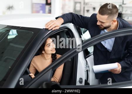 Verkäufer erklärt einer Frau die Fahrzeugmerkmale Stockfoto