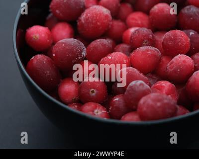 Gefrorene Preiselbeeren in einer schwarzen Schüssel. Nahaufnahme. Stockfoto