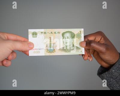 Zwei Hände, die eine Yuan-Note halten Stockfoto