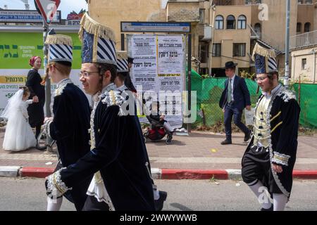 Junge Männer in Kostümen gehen während der Purim-Feier auf den Straßen. Ultraorthodoxe Juden feiern Purim in Bnei Brak, Israel. Der Feiertag erinnert an die Rettung der Juden im alten Persien durch einen Plan zur Vernichtung. Ein fröhlicher Feiertag, der sowohl von weltlichen als auch von nichtweltlichen Juden gefeiert wird, vor allem indem sie sich in Kostümen kleiden und trinken, so der Talmud, „bis sie nicht unterscheiden können zwischen ‚verflucht ist Haman‘ und ‚gesegnet ist Mordechai‘. Stockfoto