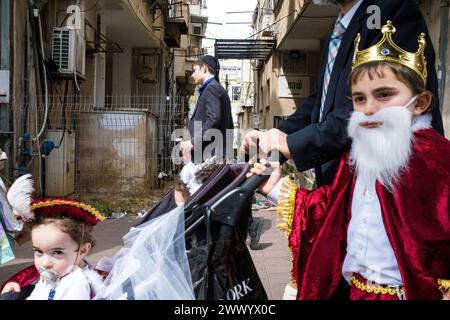 Ein Vater wird mit seinen beiden Kindern in Kostümen während der Purim-Feier gesehen. Ultraorthodoxe Juden feiern Purim in Bnei Brak, Israel. Der Feiertag erinnert an die Rettung der Juden im alten Persien durch einen Plan zur Vernichtung. Ein fröhlicher Feiertag, der sowohl von weltlichen als auch von nichtweltlichen Juden gefeiert wird, vor allem indem sie sich in Kostümen kleiden und trinken, so der Talmud, „bis sie nicht unterscheiden können zwischen ‚verflucht ist Haman‘ und ‚gesegnet ist Mordechai‘. Stockfoto