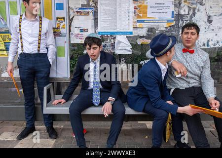Junge Männer in schicken Kleidern sitzen an einem Bustop, einer ist sichtbar betrunken während der Purim-Feier. Ultraorthodoxe Juden feiern Purim in Bnei Brak, Israel. Der Feiertag erinnert an die Rettung der Juden im alten Persien durch einen Plan zur Vernichtung. Ein fröhlicher Feiertag, der sowohl von weltlichen als auch von nichtweltlichen Juden gefeiert wird, vor allem indem sie sich in Kostümen kleiden und trinken, so der Talmud, „bis sie nicht unterscheiden können zwischen ‚verflucht ist Haman‘ und ‚gesegnet ist Mordechai‘. (Foto: Syndi Pilar/SOPA Images/SIPA USA) Stockfoto