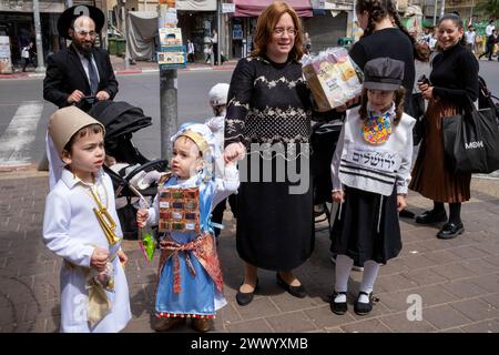 Bnei Brak, Israel. März 2024. Zwei Kinder sind als biblische Charaktere gekleidet, eines als Joshua, während das andere als Cohen oder Hohepriester gekleidet ist, das dritte junge Mädchen, das während der Purimfeier als junger Jeschiwa-Junge gekleidet ist. Ultraorthodoxe Juden feiern Purim in Bnei Brak, Israel. Der Feiertag erinnert an die Rettung der Juden im alten Persien durch einen Plan zur Vernichtung. Ein fröhlicher Feiertag, der sowohl von weltlichen als auch nichtweltlichen Juden gefeiert wird, vor allem indem sie sich in Kostümen verkleiden und trinken, so der Talmud, "bis sie nicht unterscheiden können zwischen "˜verflucht ist Haman" Stockfoto