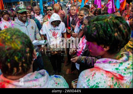 Man sieht Menschen, die traditionelle indische Musik spielen. Millionen von Menschen weltweit feiern das jährliche Holi Hangámá Festival, auch bekannt als das Festival der Farben, was bedeutet, die Ankunft des Frühlings zu feiern. In den Haag, wo die größte indische Bevölkerung Europas zu finden ist, fand im multikulturellen Viertel Transvaal eine große Feier statt, wo die Teilnehmer buntes Pulver auf sich und einander warfen. Die Leute feierten dieses Ereignis, indem sie in einer farbenfrohen Prozession durch die Nachbarschaft gingen und sangen und tanzten. Stockfoto