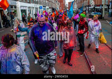 Während einer farbenfrohen Prozession werden Menschen beim Gehen gesehen. Millionen von Menschen weltweit feiern das jährliche Holi Hangámá Festival, auch bekannt als das Festival der Farben, was bedeutet, die Ankunft des Frühlings zu feiern. In den Haag, wo die größte indische Bevölkerung Europas zu finden ist, fand im multikulturellen Viertel Transvaal eine große Feier statt, wo die Teilnehmer buntes Pulver auf sich und einander warfen. Die Leute feierten dieses Ereignis, indem sie in einer farbenfrohen Prozession durch die Nachbarschaft gingen und sangen und tanzten. Stockfoto