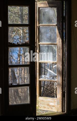 Kaputte Fenster Tür offen mit Sonnenlicht und Schatten Stockfoto