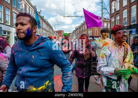 25. März 2024 in den Haag, Niederlande: Menschen werden beim Wandern beobachtet, während sie mit farbenfrohem Pulver bedeckt sind. Millionen von Menschen weltweit feiern das jährliche Holi HangÃmÃ Festival, auch bekannt als das Festival der Farben, was bedeutet, die Ankunft des Frühlings zu feiern. In den Haag, wo die größte indische Bevölkerung Europas zu finden ist, fand im multikulturellen Viertel Transvaal eine große Feier statt, wo die Teilnehmer buntes Pulver auf sich und einander warfen. Die Leute feierten dieses Ereignis, indem sie in einer farbenfrohen Prozession durch die Nachbarschaft gingen und sangen und tanzten. (Credi Stockfoto