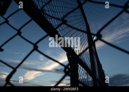 Netz und Zaun eines alten verlassenen Sportplatzes gegen Sonnenuntergang. Sportausrüstung. Stockfoto