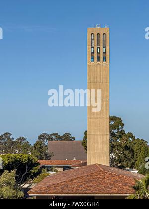 Santa Barbara, Kalifornien, USA - 17. März 2024: UCSB, Ostseite des Storke Tower über dem roten Dach der Karl Geiringer Hall unter blauem sonnigem Himmel. Grünes Laub Stockfoto