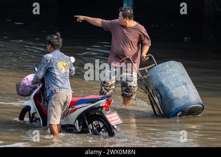 SAMUT PRAKAN, THAILAND, 11. Februar 2024, Ein Portier zeigt den Weg auf einem überfluteten Markt Stockfoto