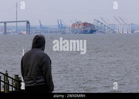 Die Zuschauer sehen die Rettungsbemühungen der Behörden, als sie nach Personen suchen, die unter den Überresten der Francis Scott Key Bridge außerhalb von Baltimore, Maryland, gefangen sind, nachdem ein Containerschiff am Dienstag, den 26. März 2024, den Strom verloren hatte und die Brücke in den frühen Morgenstunden getroffen hatte. Quelle: Aaron Schwartz/CNP Stockfoto