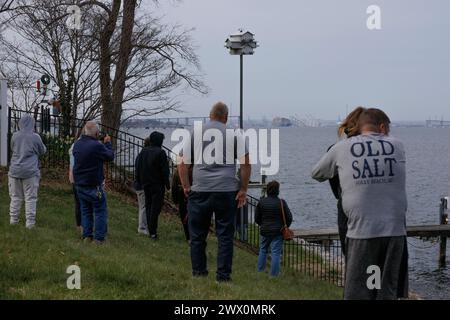 Die Zuschauer sehen die Rettungsbemühungen der Behörden, als sie nach Personen suchen, die unter den Überresten der Francis Scott Key Bridge außerhalb von Baltimore, Maryland, gefangen sind, nachdem ein Containerschiff am Dienstag, den 26. März 2024, den Strom verloren hatte und die Brücke in den frühen Morgenstunden getroffen hatte. Quelle: Aaron Schwartz/CNP Stockfoto