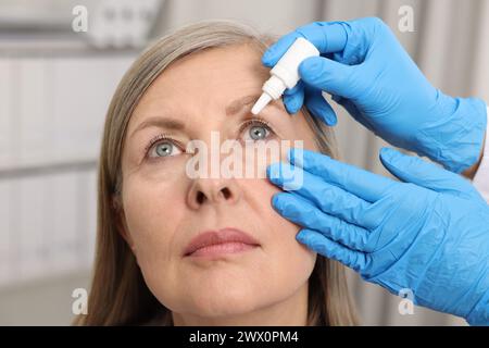 Medizinische Tropfen. Doktor tropft Medikamente in das Auge der Frau drinnen Stockfoto