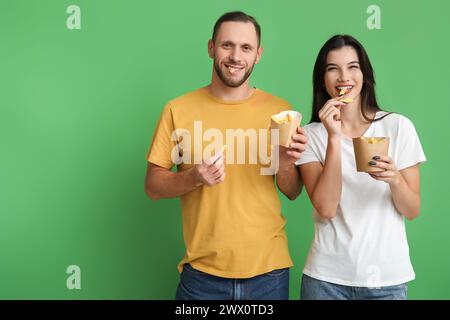 Schönes junges Paar, das Pommes frites auf grünem Hintergrund isst Stockfoto