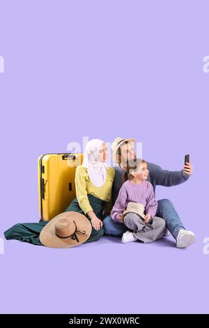 Wunderschöne muslimische Familie mit Koffer, die Selfie auf Fliederhintergrund macht. Reisekonzept Stockfoto