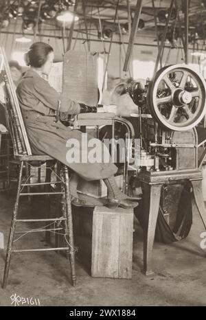 (Originalunterschrift) Arbeiterinnen in Munitionsanlagen: Frau, die an einer Verschließmaschine in der Fabrik der US-amerikanischen Cartridge Company in Lowell, MA CA. Arbeitet. 1919 Stockfoto