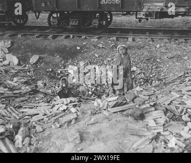 Obdachlos suchen Bruder und Schwester leere Dosen nach Lebensmitteln und versuchen, sich neben einem kleinen Feuer in Seoul, Korea, den Bahnhöfen CA warm zu halten. November 1950 Stockfoto