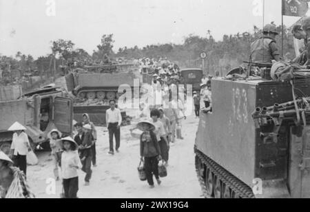 Vietnam-Krieg: M-113 gepanzerte Personalträger stehen bereit, während vietnamesische Flüchtlinge während der Tet-Offensive CA das Dorf My Tho in der Provinz Dinh Tuong evakuieren. 1968 Stockfoto