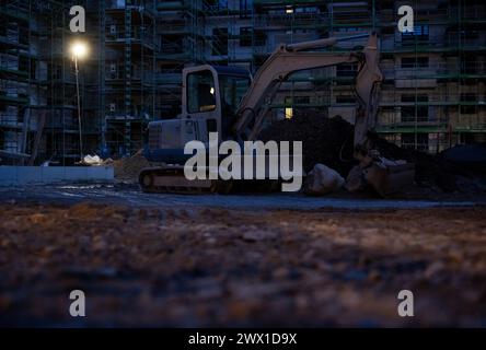 München, Deutschland. März 2024. Ein Bagger steht vor einem Gerüst auf einer Baustelle im Rohbau eines neuen Gebäudes. Quelle: Sven Hoppe/dpa/Alamy Live News Stockfoto