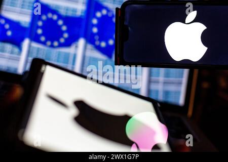 Auf diesem Foto ist das Logo von Apple auf einem Smartphone und Tablet-Bildschirm vor einem Bildschirm zu sehen, auf dem ein Foto der Flaggen der Europäischen Union abgebildet ist. Stockfoto