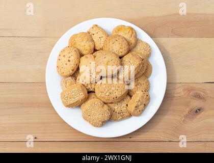 Verschiedene Kekse und Kekse in weißer Keramikplatte auf hölzernem Hintergrund Stockfoto