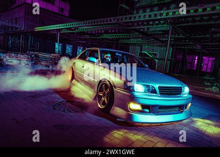 High Speed Night Drift mit maßgeschneidertem Sportwagen in urbaner Umgebung Stockfoto