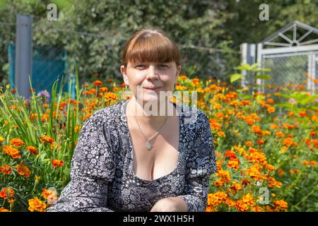 Frau, die in Tagetes Blumen im Garten sitzt Stockfoto