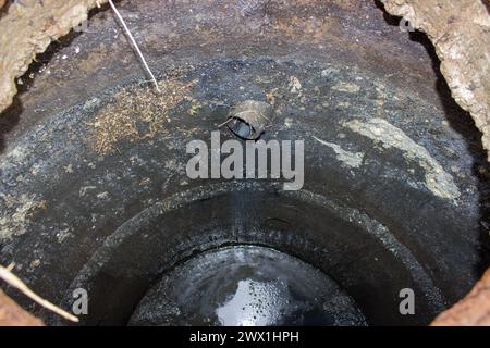 Gefährlich offene Entwässerungsgrube mit Schmutz und schwarzer Sumpf mit Wasser Stockfoto