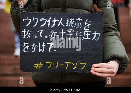 Die Aktivistin hält ein Banner mit dem Titel „Rotes Kreuz, ihr genehmigt die Folter von Kriegsgefangenen passiv“ in japanischer Sprache bei einer Kundgebung, die den Kriegsgefangenen gewidmet ist, die in russischen Gefängnissen bleiben. Kiew - 24. März 2024 Stockfoto