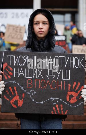 Die ukrainische Frau hält das Banner „Tausende von Teilen unserer Seelen sind in Gefangenschaft“ bei einer Kundgebung „Freies Asov“, die den gefangenen Verteidigern Mariupols gewidmet ist. Kiew - 24. März 2024 Stockfoto