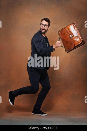 Aktentasche, Mode und Mann im Studio mit Brille für trendiges, trendiges und stylisches Outfit mit Selbstvertrauen. Goofy, Umhängetasche und Person mit Blazer für Stockfoto