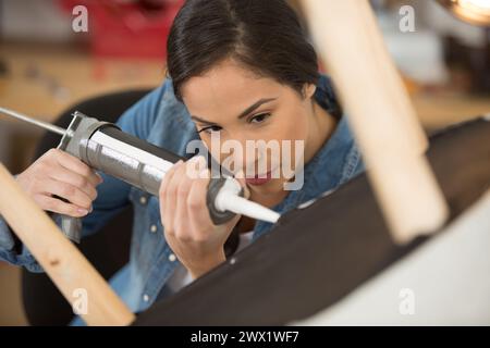 Frau, die Silikon benutzt, um einen Stuhl zu kleben Stockfoto