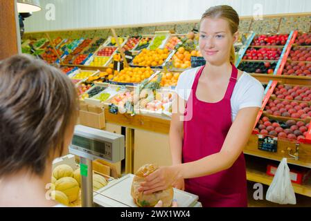 Ladenassistent, der Obst für den Kunden wiegt Stockfoto