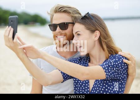 Lässig gekleidetes Paar, das Selfie am Strand macht Stockfoto