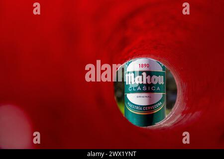 Das Bier der Marke Mahou kann durch eine rote Röhre und einen Hintergrund in der Umgebung gesehen werden Stockfoto