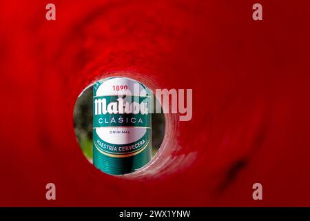 Das Bier der Marke Mahou kann durch eine rote Röhre und einen Hintergrund in der Umgebung gesehen werden Stockfoto