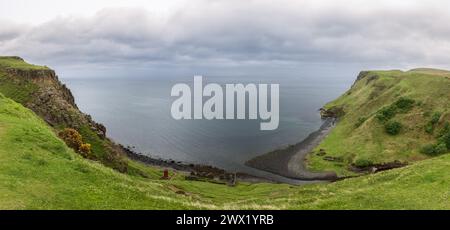 Dieses atemberaubende Panorama fängt die dramatische Küste nahe den Lealt Falls auf der Isle of Skye ein, wo grüne Klippen auf die graue Ruhe des Meeres treffen Stockfoto