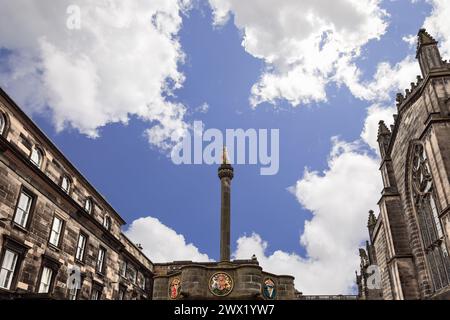Das historische Mercat Cross mit seinem glitzernden goldenen Einhorn steht stolz auf dem Parliament Square in Edinburgh vor dem Hintergrund eines kunstvoll verzierten Steingebäudes Stockfoto
