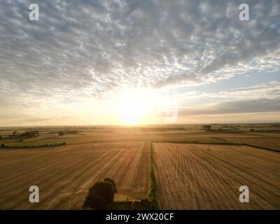 Ein Blick aus der Vogelperspektive auf den Sonnenaufgang über einem Bauernhof auf dem Land Stockfoto