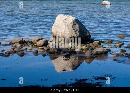 Große Felsen mit Steinen liegen im Wasser an der Ostseeküste, mit Reflexion Stockfoto