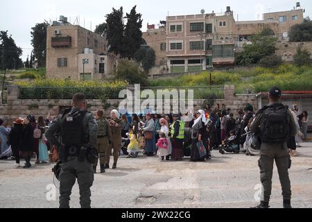 Jüdische Siedler in Kostümen tanzen während der jährlichen Purim-Parade, während israelische Sicherheitskräfte die Feierlichkeiten am 24. März 2024 in Hebron sichern. Stockfoto