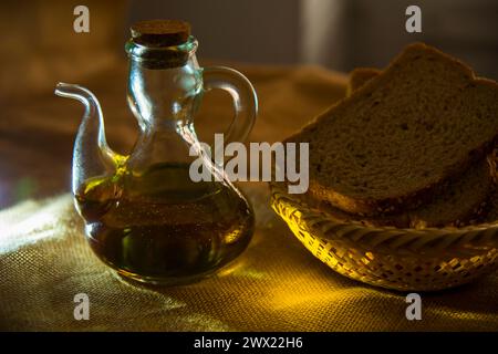 Stillleben: Ölflasche und Brot in einem Korb. Schließen Sie die Ansicht. Stockfoto