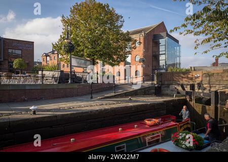 Merchants Warehouse in Castlefield, Manchester, mit einem Kanalboot, das im Vordergrund eine Schleuse auf dem Rochdale Canal fährt Stockfoto