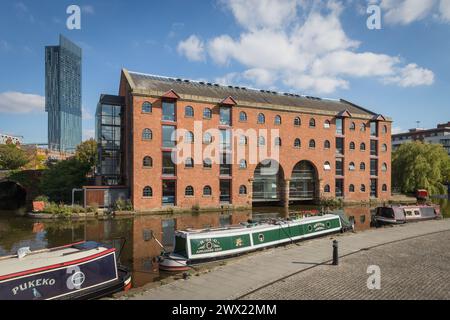 Merchants Warehouse in Castlefield, Manchester, mit Kanalbooten, die im Vordergrund am Bridgewater Canal verankert sind Stockfoto