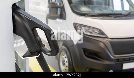 Elektrischer Lieferwagen mit Ladestation für Elektrofahrzeuge. Stockfoto